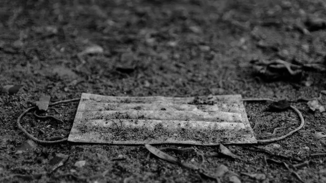 A covid mask lays discarded on the ground